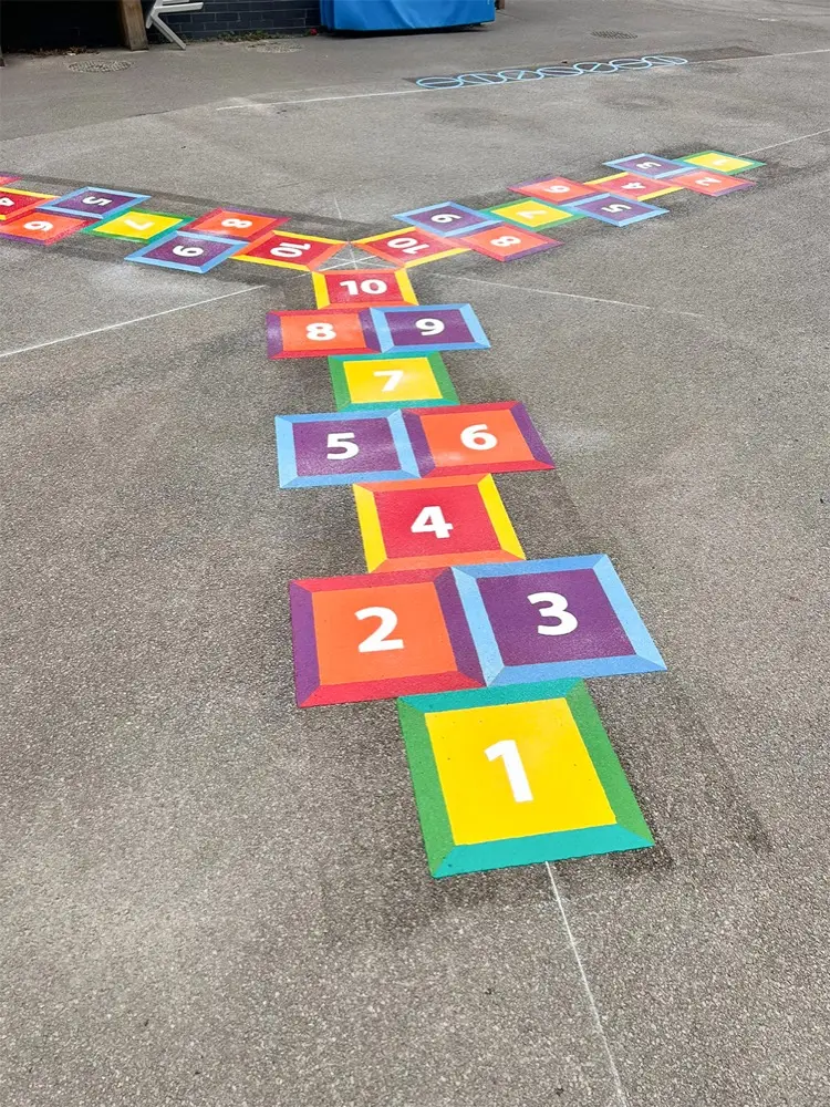 3 Way Hopscotch in thermoplastic with bevelled multicoloured squares numbered 1 to 10, splitting into two arms on grey tarmac